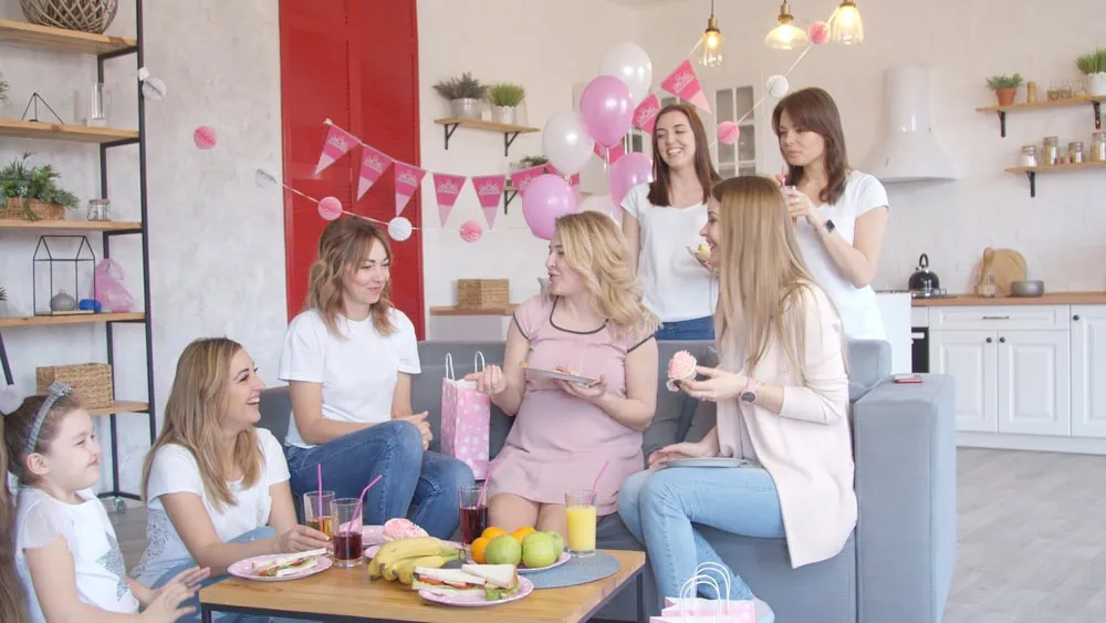 webbabyshower mom chatting with friends at baby shower party with little foods and drinks